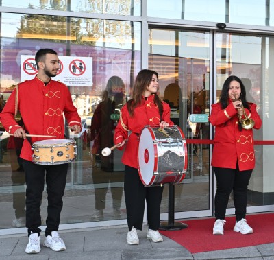 A group of musicians in red uniforms playing instruments like drums, trumpet, and saxophone at SIGN İstanbul entrance