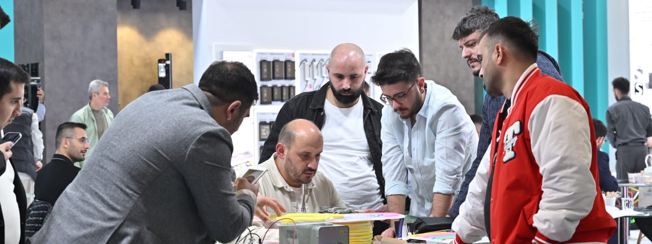 Group of exhibitors discussing and exploring a product display at the Sign Istanbul stand