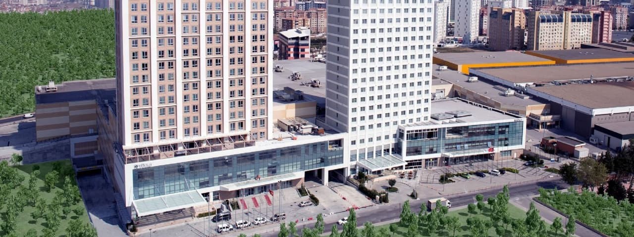 Exterior view of Tuyap Palas Hotel with a modern design surrounded by trees and other city structures