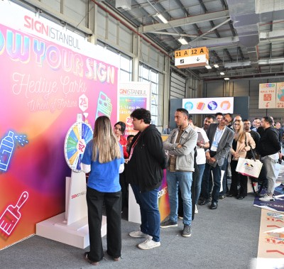 Attendees engaging with colorful neon signs at SIGN İstanbul, with illuminated displays