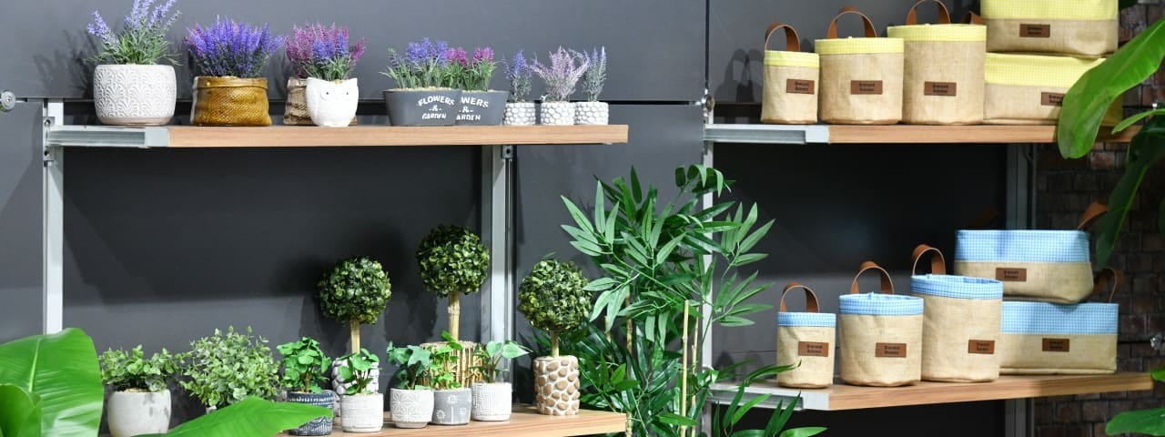 Toprak ve rengarenk çiçeklerle dolu bir ürün grubu rafı.