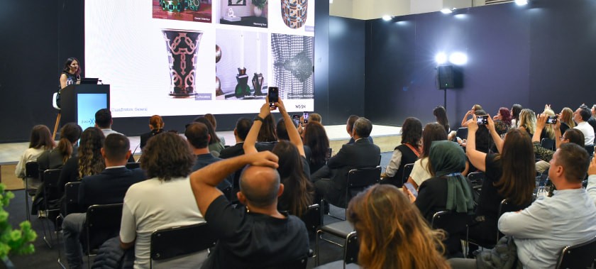 ZuchXTalks’ta bir semineri dinleyen ziyaretçiler, yansıtılan sunumdan fotoğraflar çekiyor.