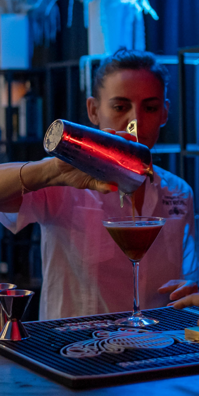 Person pouring drink into a martini glass