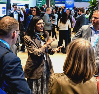 Person in a busy exhibit hall speaking to a crowd